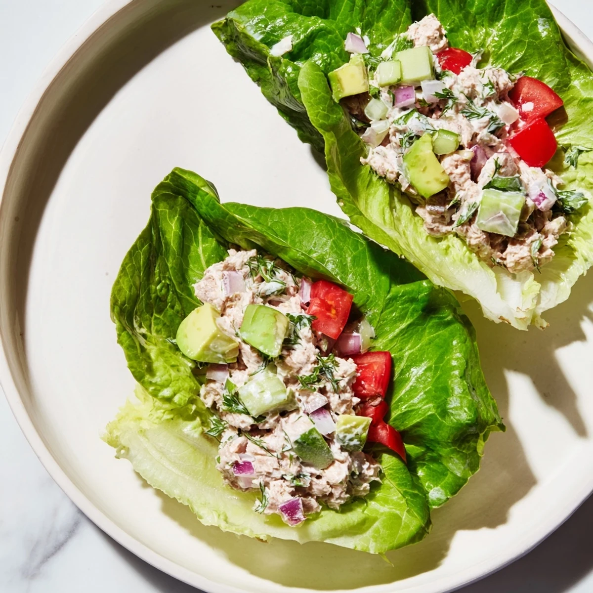 Healthy tuna salad lettuce wraps, creamy and vibrant, served with fresh avocado slices on crisp romaine.