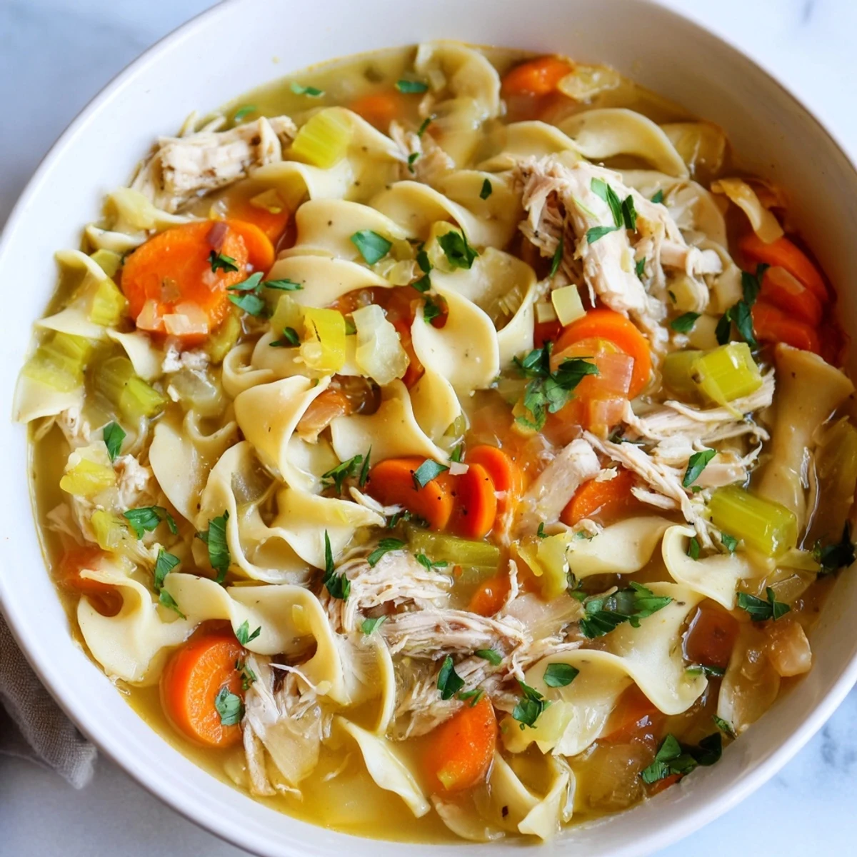 Steaming bowl of Cozy Chicken Noodle Soup from Scratch, filled with tender chicken and golden noodles.