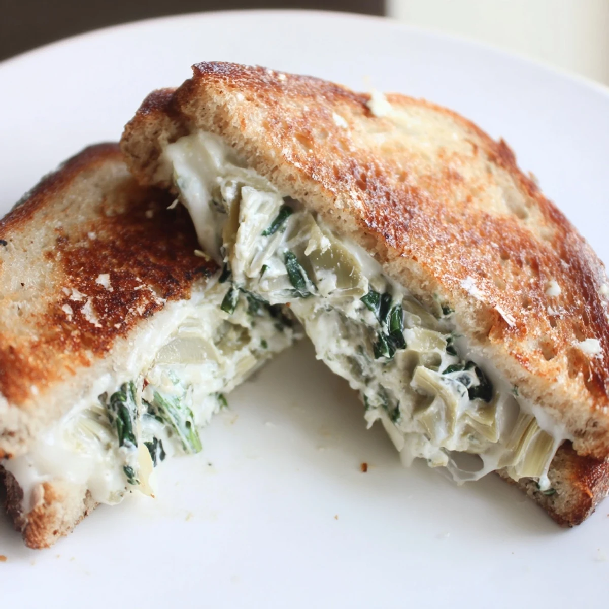 Golden, crispy sourdough slices are stuffed with creamy spinach artichoke grilled cheese, melted mozzarella oozing from the edges.