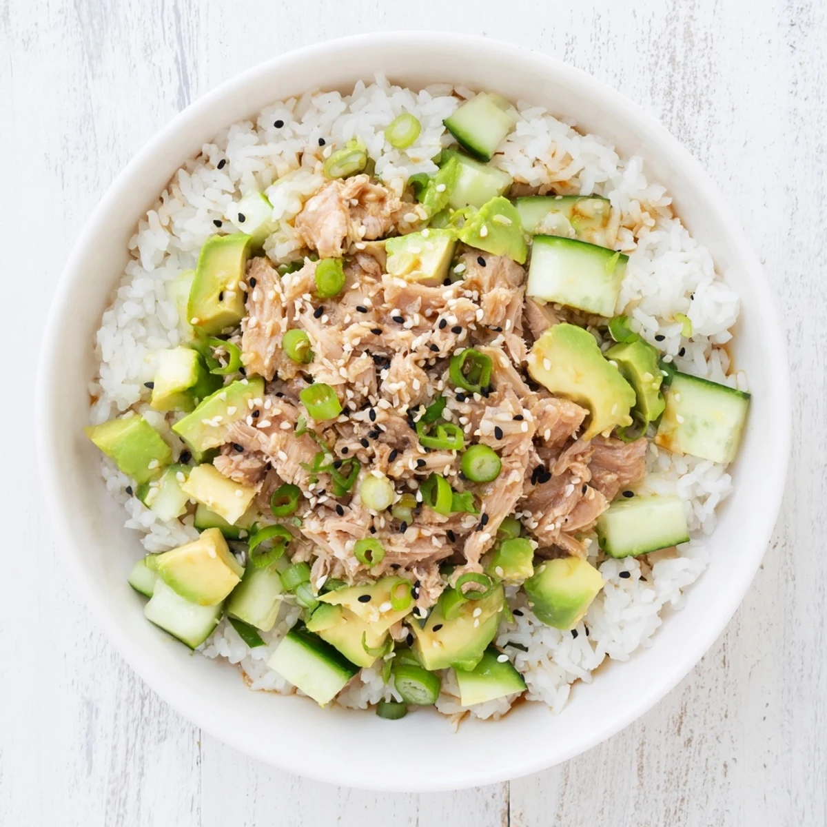 Fluffy jasmine rice topped with tender tuna, creamy avocado, and crisp cucumber in a vibrant bowl.