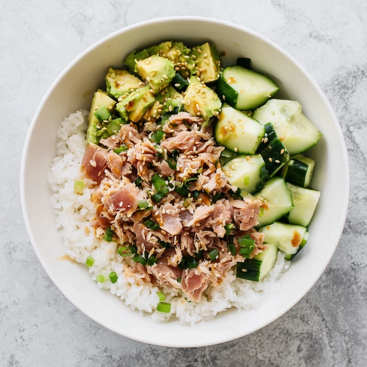 Colorful fusion dish featuring flaked tuna, diced avocado, and scallions over warm jasmine rice.