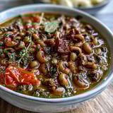 Greek-Style Slow Cooker Black-Eyed Peas simmer in a rich tomato and oregano broth inside a slow cooker, emitting steam.