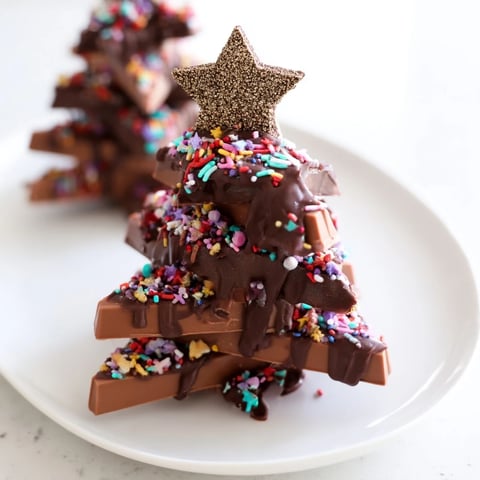 Chocolate Kinder Christmas Trees, a festive dessert, drizzled in melted chocolate with colorful sprinkles.