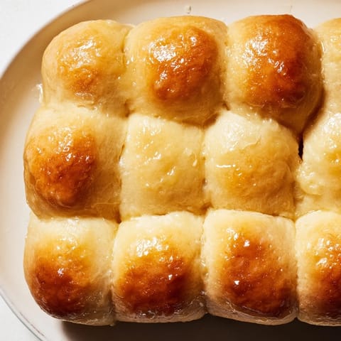Freshly baked homemade golden dinner rolls, glistening with melted butter, perfect for any holiday feast.