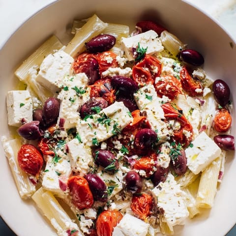 A close-up of vibrantly red Baked Feta Pasta, ready to serve with fragrant basil garnish.