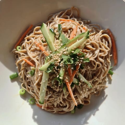 A flavorful bowl of Cold Sesame Noodles, glistening with delicious sauce and fresh cilantro garnish.