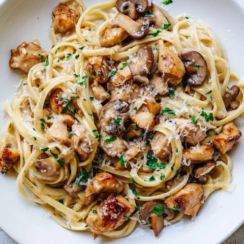 This close-up shows delicious creamy mushroom chicken pasta, perfect with fettuccine and Parmesan cheese.