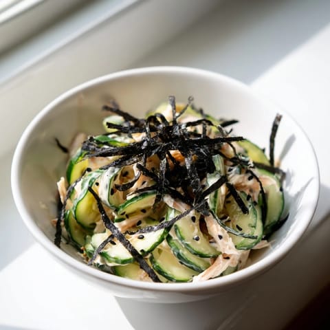 A vibrant bowl of California Roll Cucumber Salad with creamy mayo dressing, imitation crab, and crunchy sesame seeds.