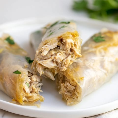 Garlicky pulled chicken wraps filled with crisp lettuce, carrot, and cucumber, pan-fried until golden and served warm with fresh parsley.  