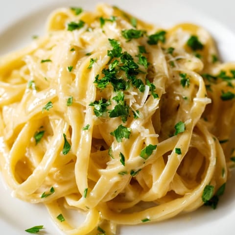 A close-up of steaming Sriracha Honey Pasta twirled on a fork, showcasing its glossy, spicy-sweet garlic butter coating.