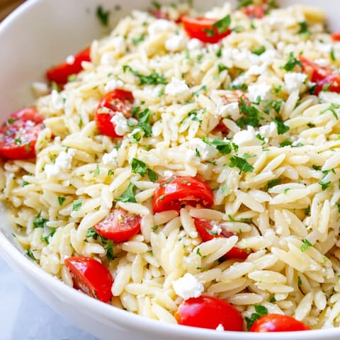Bright Mediterranean flavors in Greek Orzo Salad, featuring feta, olives, and herbs on a sunny picnic table.  