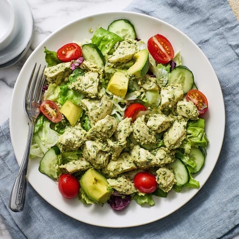 Vibrant Green Goddess Chicken Salad with crisp greens, cherry tomatoes, and sliced avocado.  