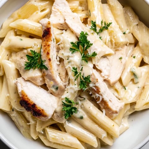 Savory Roasted Garlic Chicken Penne served steaming hot, topped with extra Parmesan and a side of crisp white wine.  