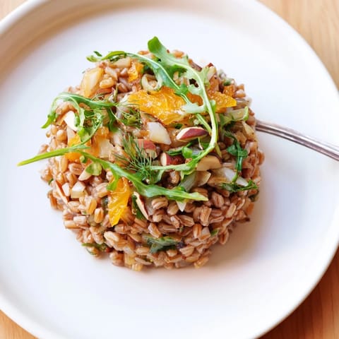 Freshly prepared Farro Salad With Fennel, Oranges, and Almonds, featuring creamy citrus vinaigrette drizzled over the wholesome Mediterranean-inspired ingredients.  