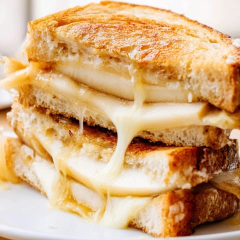 Golden-brown grilled cheese sandwich featuring smoked Gouda and tart apple slices, perfect for a cozy lunch paired with tomato soup.