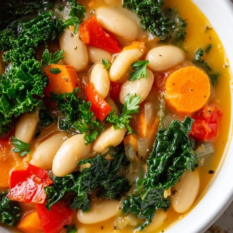 Hearty Mediterranean White Bean Stew simmered with kale, carrots, and red bell peppers in a rich broth.  