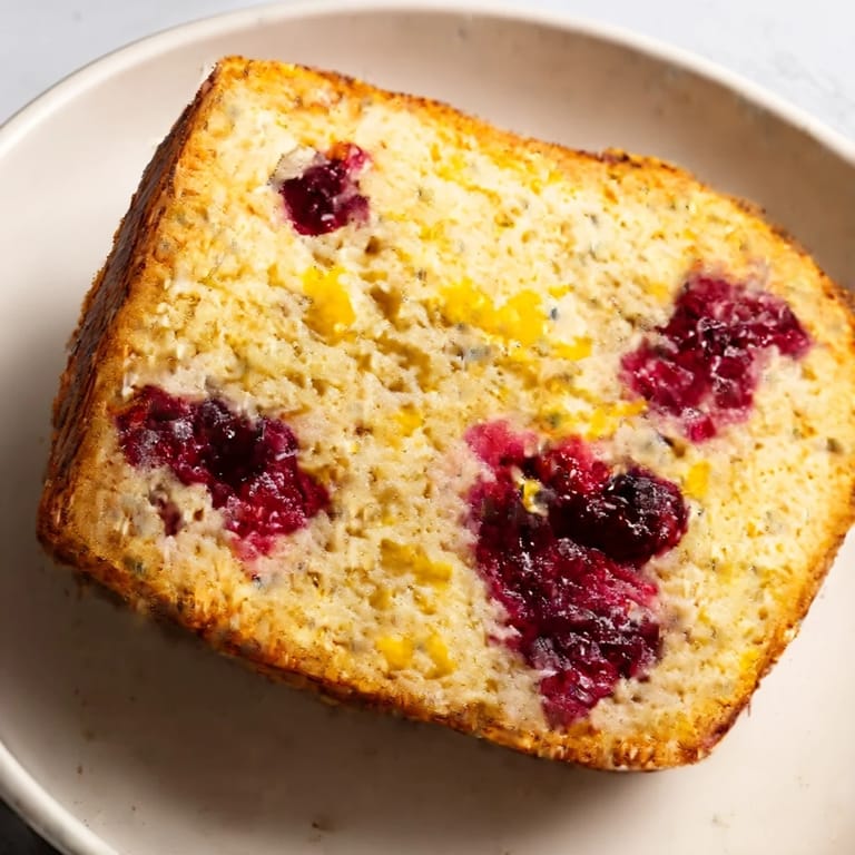 A rustic loaf of Seasonal Cranberry and Orange Bread, studded with cranberries, suggesting a moist, delightful texture.