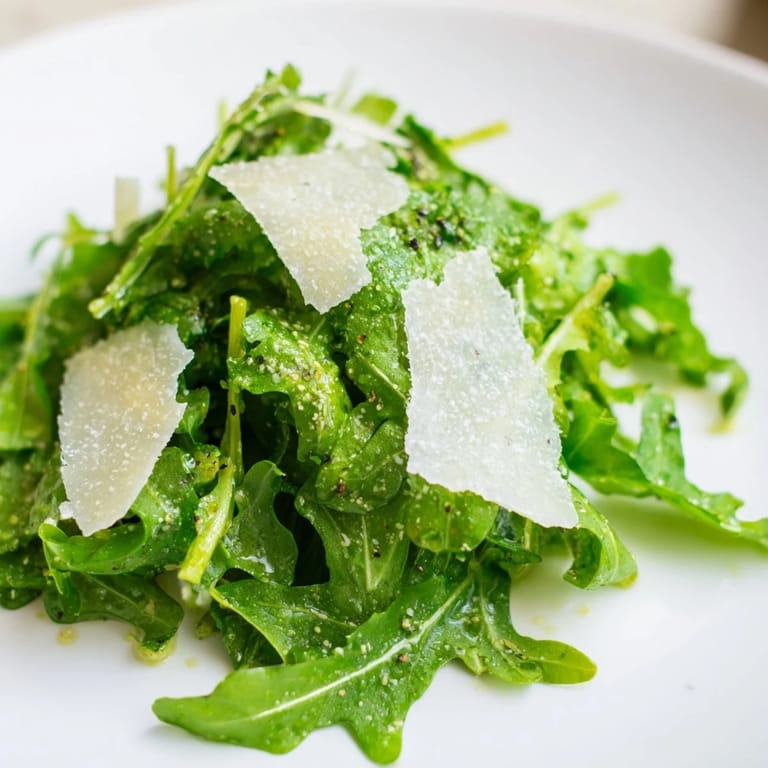 Close-up of the easy arugula salad: peppery greens, drizzled lemon dressing, and shaved Parmesan.
