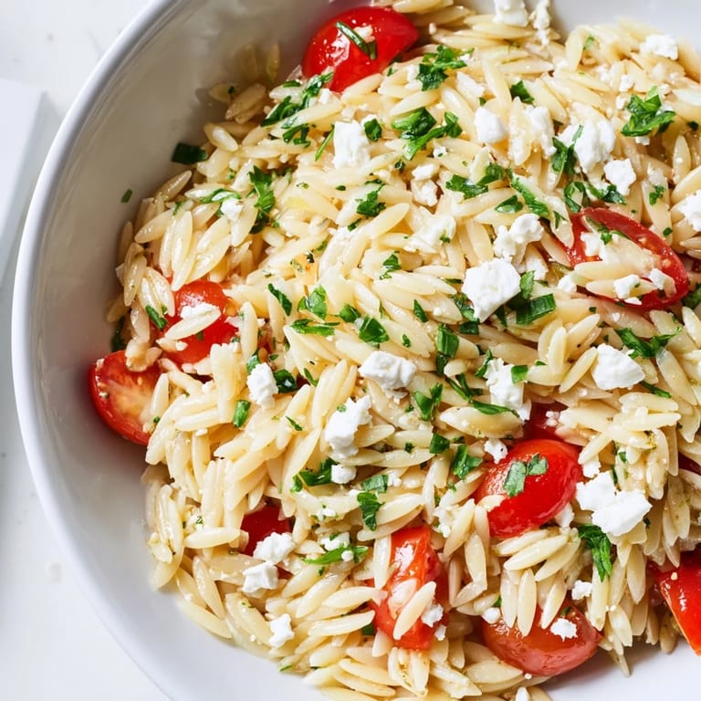 Colorful Greek Orzo Salad plated for summer potlucks, with diced veggies, crumbled feta, and zesty dressing.