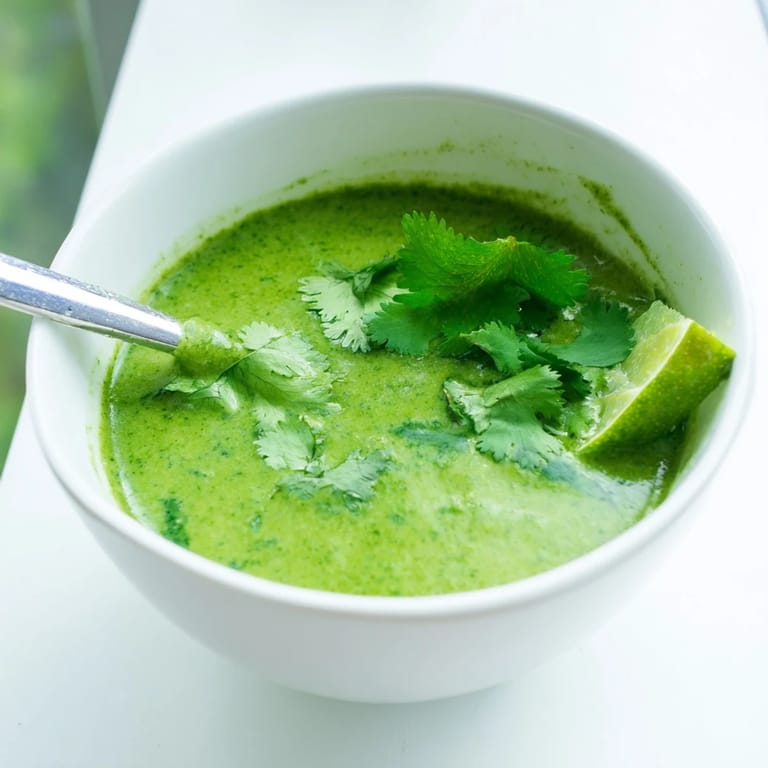 Close-up of a ladle pouring silky Spinach Coriander Lemongrass Soup into a bowl, highlighting its rich, emerald color.