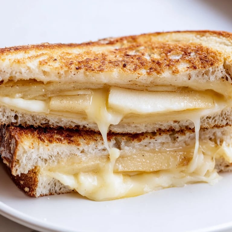 Buttery, grilled sandwich layers of smoky Gouda cheese and crisp apple slices between golden sourdough bread, ready to serve.